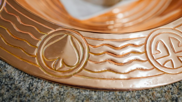 En kop af kopper med indgraveret hjerte og bølger.