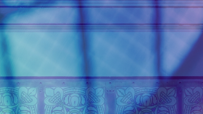 Farvet glasvindue med indviklede blomster- og geometriske mønstre oplyst af blødt lys.