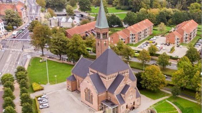 En kirke med tårn i en bydel med huse og træer