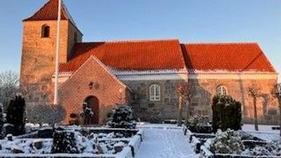 En fredfyldt vinterscene af en historisk kirke med snedækkede havegange og klippede hække.