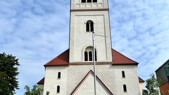 Weiße Kirche mit hohem Glockenturm und rotem Dach.