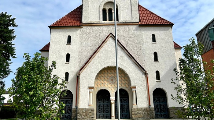Weiße Kirche mit hohem Glockenturm und rotem Dach.