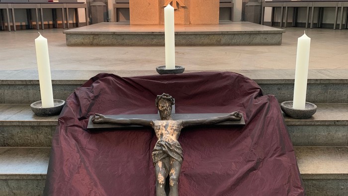 Ein Kreuz mit Jesusfigur steht vor einem Altar in einer Kirche