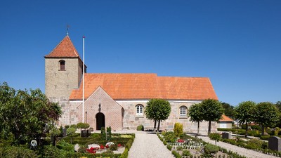 En smuk kirke med rødt tag og en lille have foran