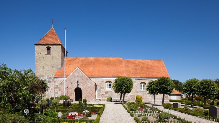 En smuk kirke med rødt tag og en lille have foran