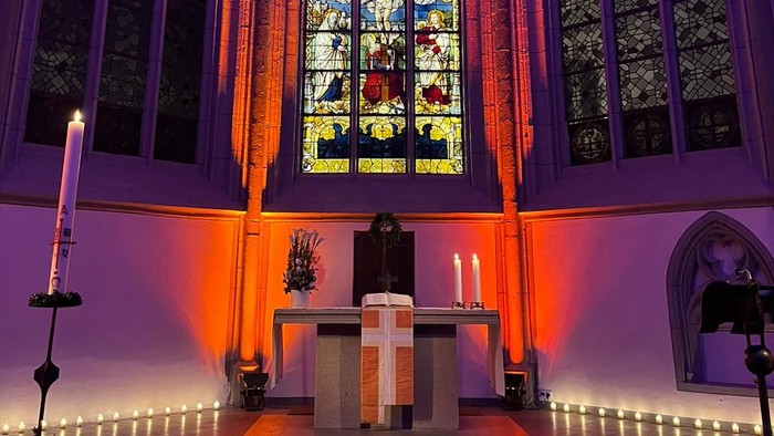 In der Kirche brennt eine Kerze vor einem Altar.