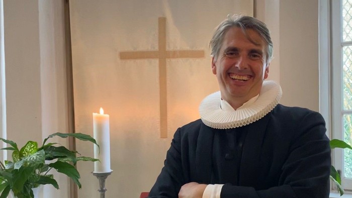 Mand i svart kapittel i kirke.