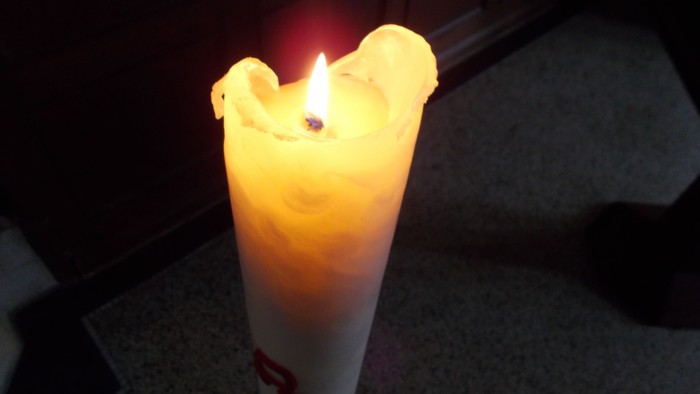 Eine brennende Kerze steht auf einem Tisch.