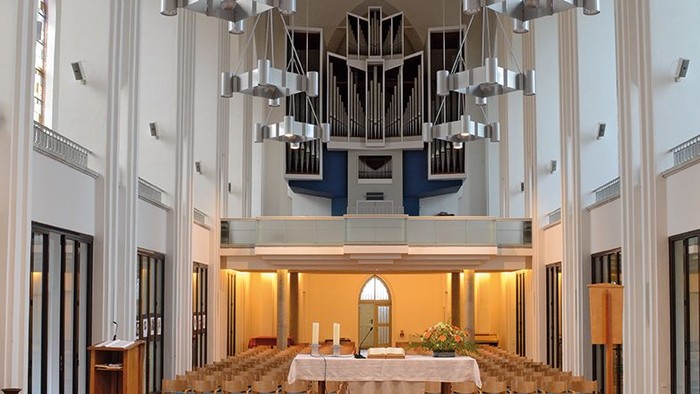 Große, helle Kirche mit hängenden Lampen und Altar