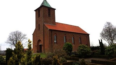 En rød murstenskirke med spiret og klokketårn.