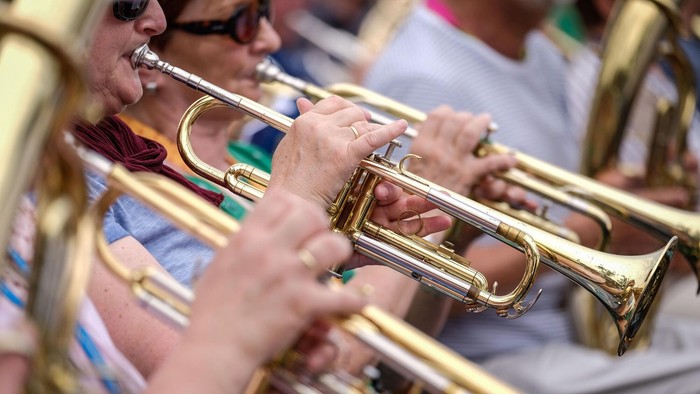 Das Bild zeigt einige Personen die ein Blasinstrument spielen.