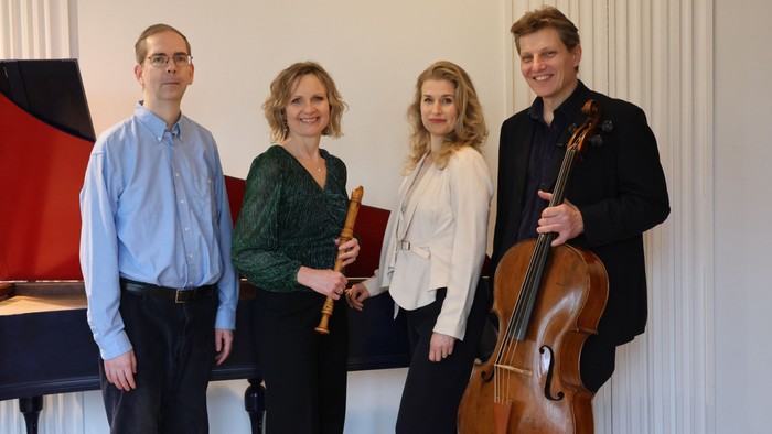 Musikere poserende med en klarinet, klaver og cello i en formel indendørs indstilling.