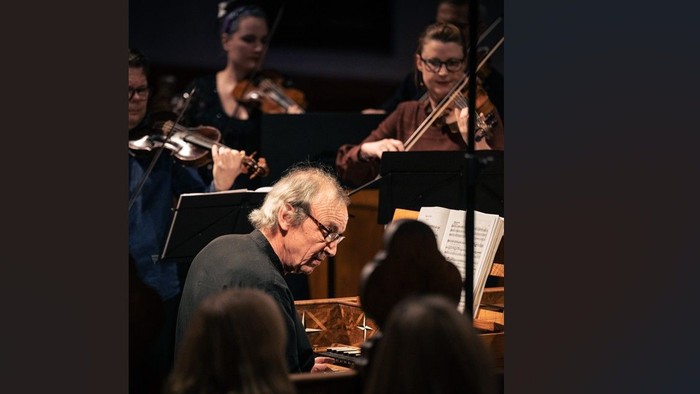 Orkester, der optræder med en dirigent, som leder fra klaveret under en koncert.