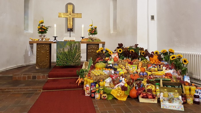 In der Kirche stehen Blumen und Kerzen vor einem Altar mit Kreuz.