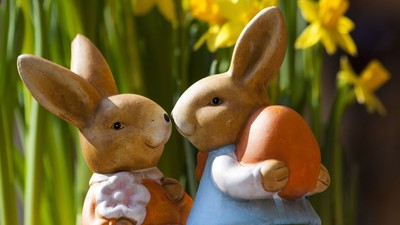 To bjørne holdes sammen af en orange æg og er placeret foran gule krokus.