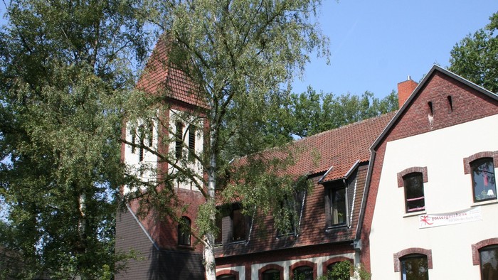 Vor einem großen Haus parken mehrere blaue Autos.