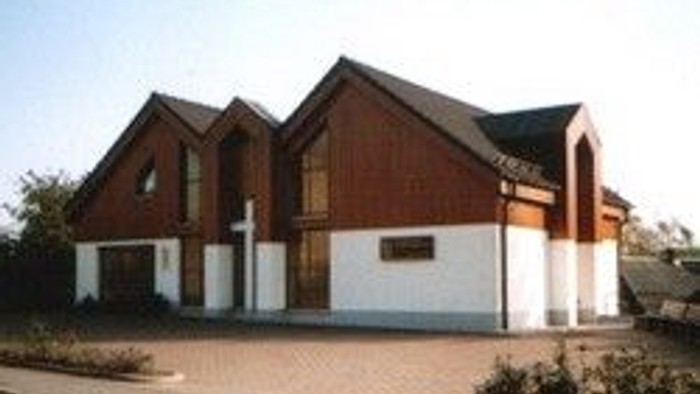 Das Bild zeigt ein zweistöckiges Haus mit braun-weißen Farben und einem Dach mit mehreren Giebeln.