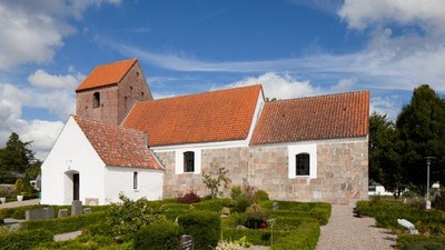 En smuk kirke med røde tag og grønne planter i forgrunden