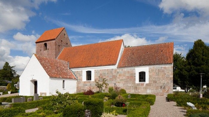 En smuk kirke med røde tag og grønne planter i forgrunden