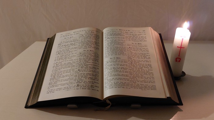 Offenes Buch auf Tisch neben brennender Kerze