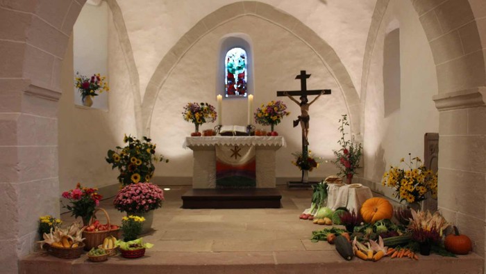 Kirchenaltar mit Kreuz, Blumen und Kürbissen