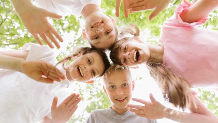Kinder, die lächeln und sich zur Kamera hin strecken.
