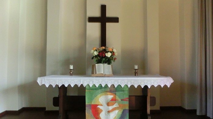 Kirchenaltar mit Kreuz, Kerzen und Blumen