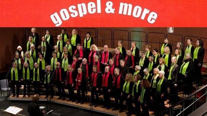 Ein großer Chor in einheitlichen grünen Westen, der Gospel und andere Musik auf der Bühne aufführt.