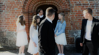 En gruppe mennesker står sammen udenfor et murstensgårdeindrag