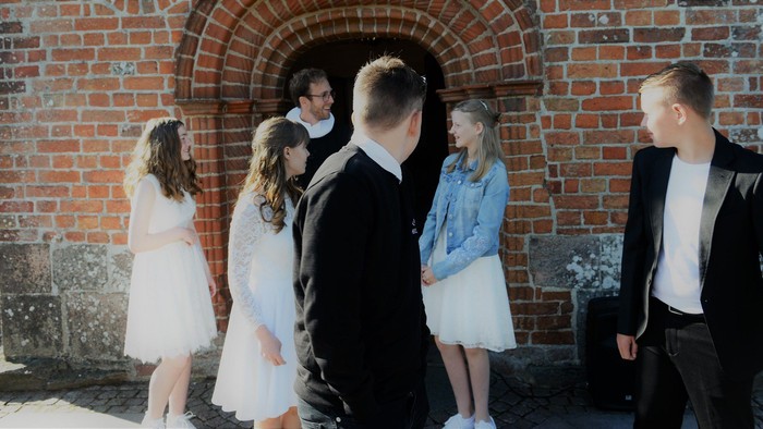 En gruppe mennesker står sammen udenfor et murstensgårdeindrag