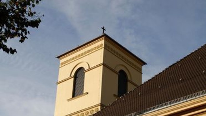Eine historische Kirche mit einem hohen Glockenturm und Bogenfenstern unter einem klaren Himmel.