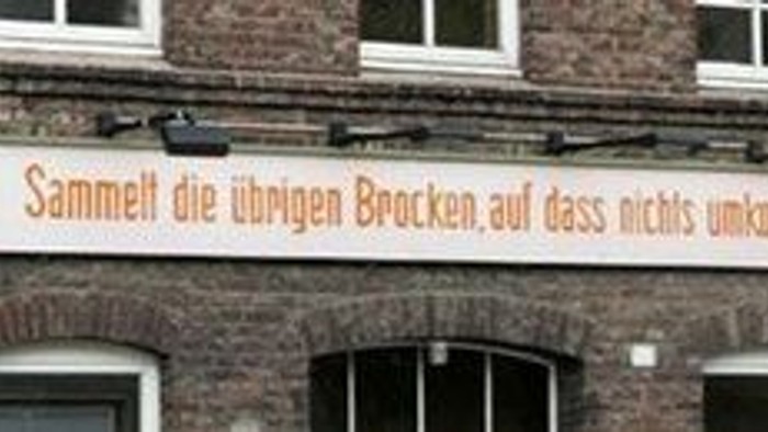 Das Bild zeigt ein Backsteingebäude mit einem großen Schild in deutscher Sprache.