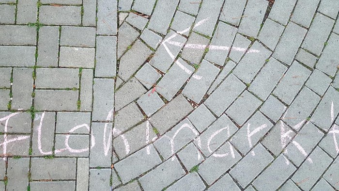 Weiße Kreide, die „Fleischmarkt“ auf ein gepflastertes Kopfsteinpflaster schreibt, mit einem Pfeil nach oben zeigend.