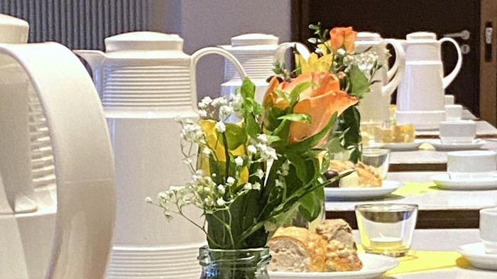 Elegante Buffettafel mit Gebäck, Blumen und verschiedenen Gerichten auf weißen Tellern mit grünen Tischläufern.