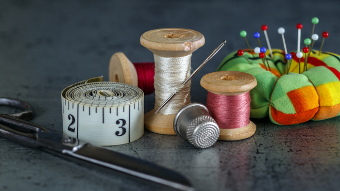 Billedet viser sy- og måleinstrumenter på en tæppe.