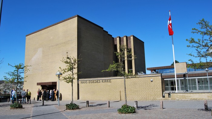 Stor bygning med flag og træer foran