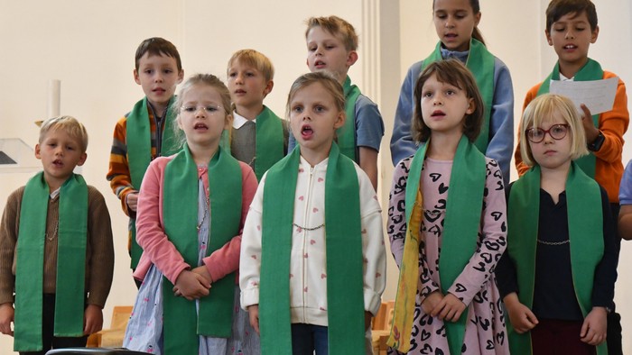 Kinder der Gemeinde Heilig Geist singend in zwei Reihen mit grüner Stola um die Schultern