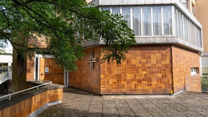 Das Bild zeigt eine Kirche mit Ziegelmauer und Kreuz.