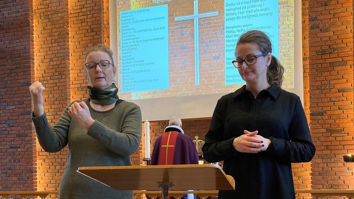 To women står ved pulpet i kirke