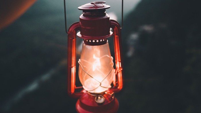 Hand holding red lantern against mountainous backdrop