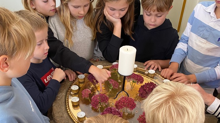 Børn samlede sig omkring et bord med en kage og lys.