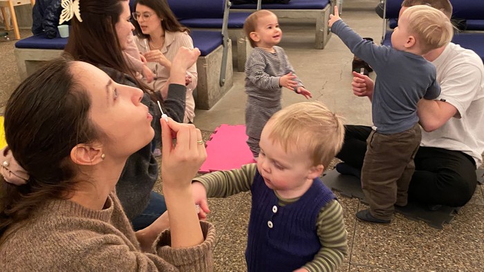 En gruppe børn og voksne spiller et interaktivt spil med farverige kort i et rummeligt indendørs område.
