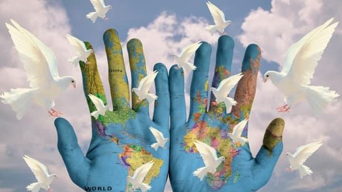 Hands holding globe with doves flying around