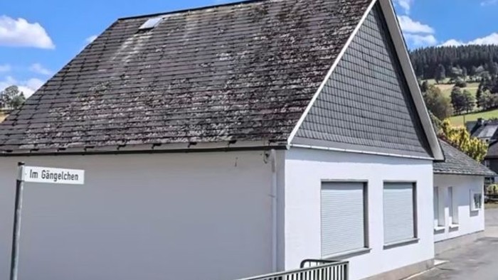 Weißes Gebäude mit schwarzem Dach und Metallzaun, Im Gingelchen.