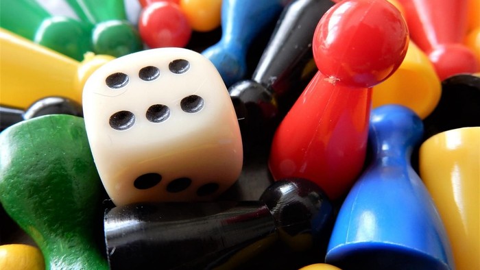Bunte Spielfiguren und Würfel wild durcheinander verstreut.
