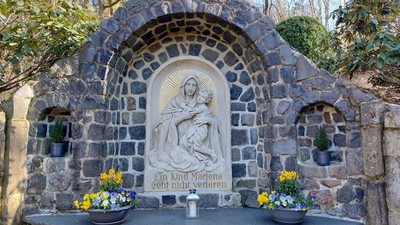 Steinbogenkapelle mit Marienstatue und Blumen
