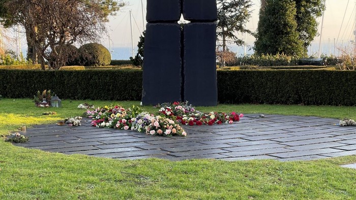 En stor sort mindeplade med blomster tilføjet ved basen.