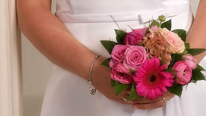 En person holder en blomstekake med rosa og pink farver.