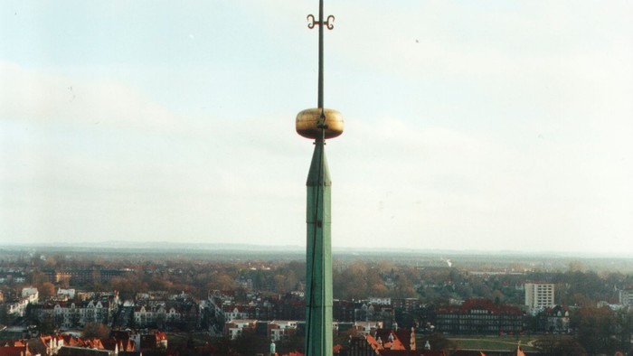 Ein hoher Turm mit Wetterfahne über einem Dorf