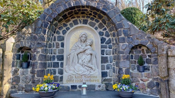 Steinbogenkapelle mit Marienstatue und Blumen